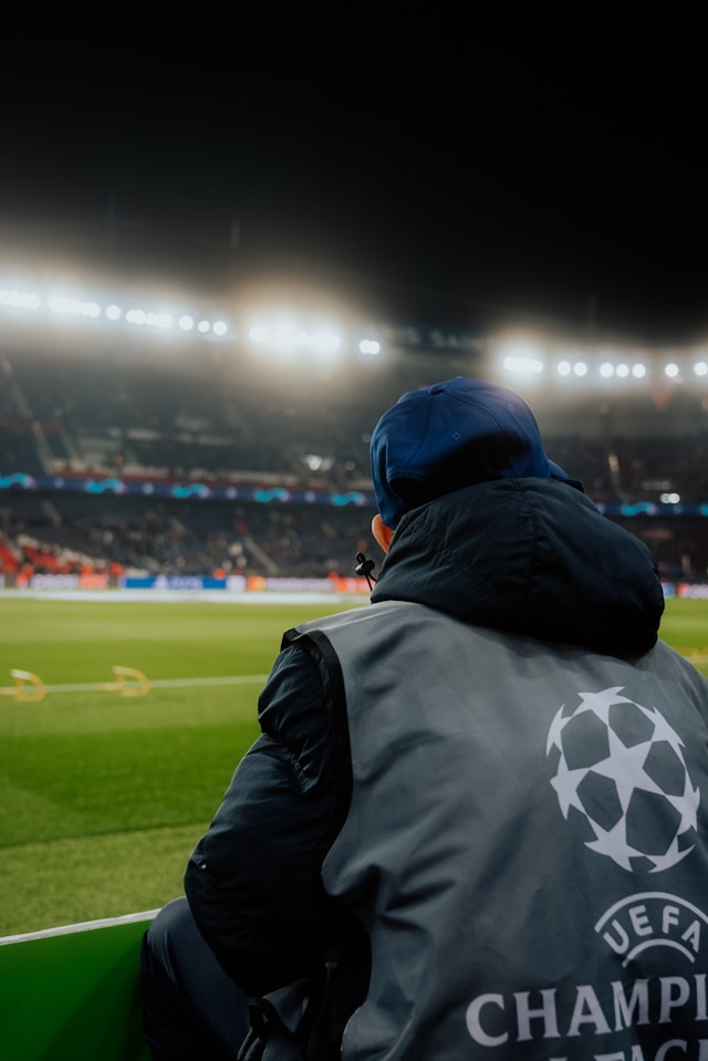 A photo of a man sitting next to the pitch of Paris Saint Germain's stadium, the Parc des Princes.